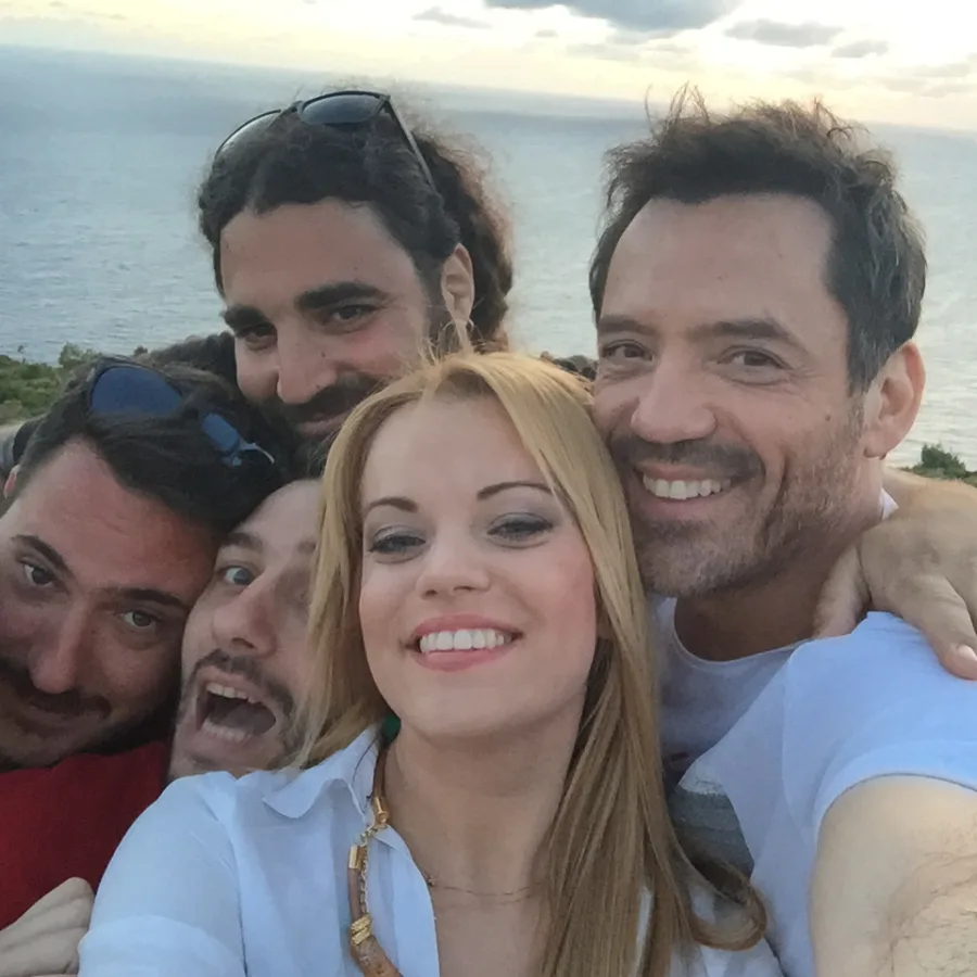 Ο Θάνος Καλλίρης με συνεργάτες σε εξωτερικό χώρο δίπλα στη θάλασσα.