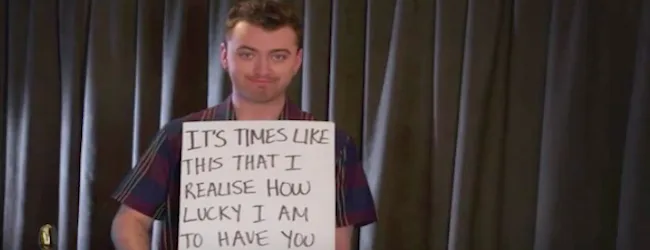 Ο Sam Smith κρατάει χειρόγραφη πινακίδα.