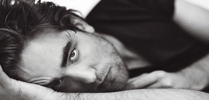 Ασπρόμαυρο κοντινό πλάνο του Robert Pattinson ξαπλωμένου.