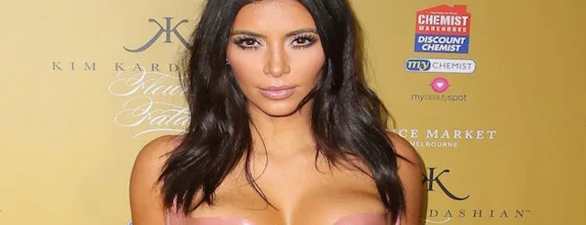 Η Kim Kardashian σε εκδήλωση με φόντο χρυσό τοίχο.