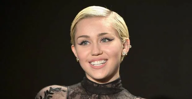 Η Miley Cyrus χαμογελάει σε εκδήλωση.