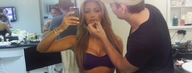 Η Kim Kardashian βγάζει selfie ενώ ένας makeup artist την βάφει.