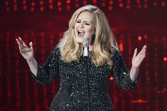 Η Adele τραγουδάει στη σκηνή με μαύρο φόρεμα με παγιέτες.