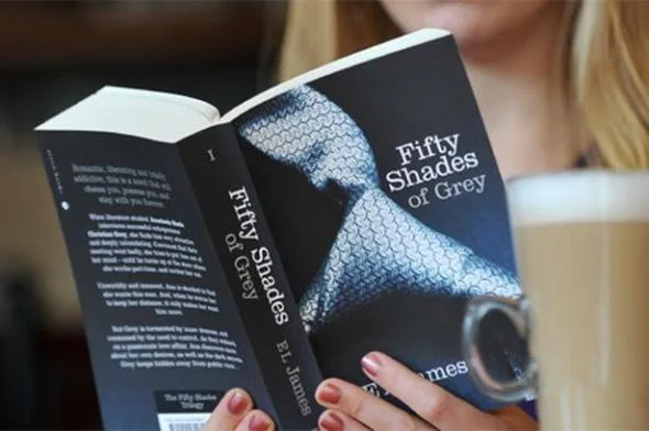 Γυναίκα διαβάζει το βιβλίο Fifty Shades of Grey της E. L. James.