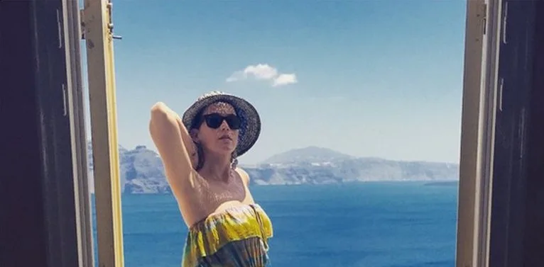Η Katy Perry με καπέλο και γυαλιά ηλίου μπροστά από το απέραντο γαλάζιο της θάλασσας.