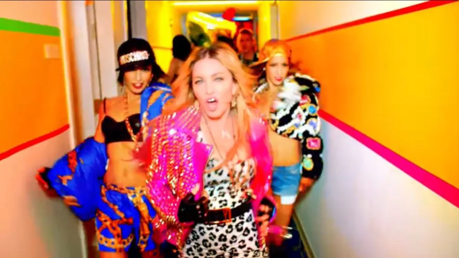 Η Madonna με χρωματιστό ντύσιμο σε διάδρομο από το video clip Bitch I’m Madonna.