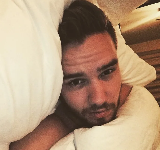 Ο Liam Payne ξαπλωμένος στο κρεβάτι ανάμεσα σε μαξιλάρια.