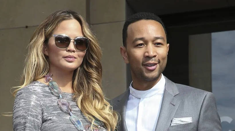 Η Chrissy Teigen και ο John Legend σε εξωτερικό χώρο.
