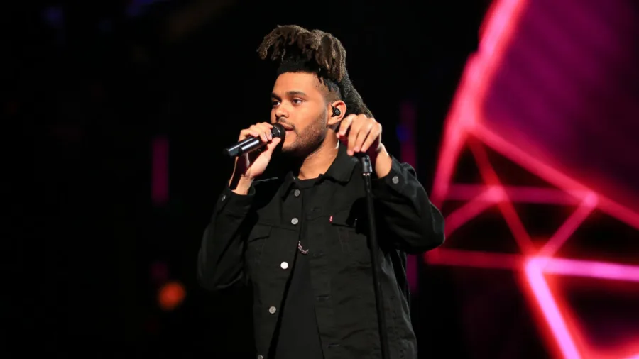 Ο Weeknd τραγουδάει στη σκηνή κρατώντας μικρόφωνο.