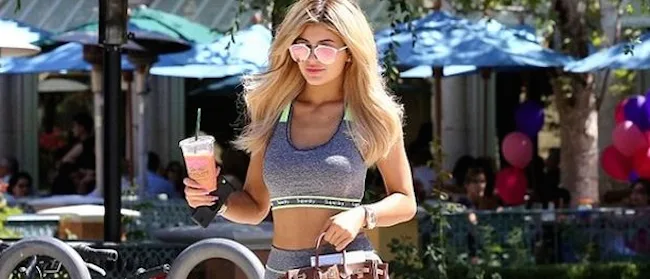 Η Kylie Jenner με αθλητικό σύνολο και γυαλιά ηλίου κρατώντας καφέ.
