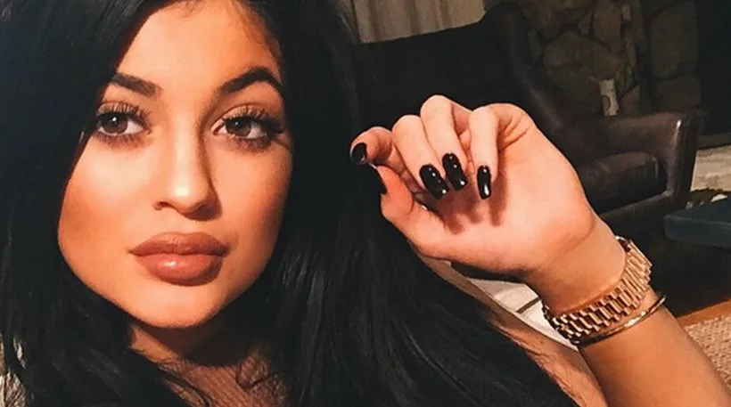 Η Kylie Jenner με έντονο μακιγιάζ, μαύρα νύχια και χρυσό ρολόι.