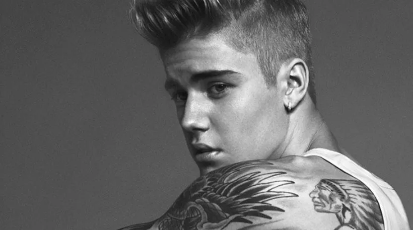 Ασπρόμαυρο κοντινό πλάνο του Justin Bieber που δείχνει τα τατουάζ στον ώμο του.