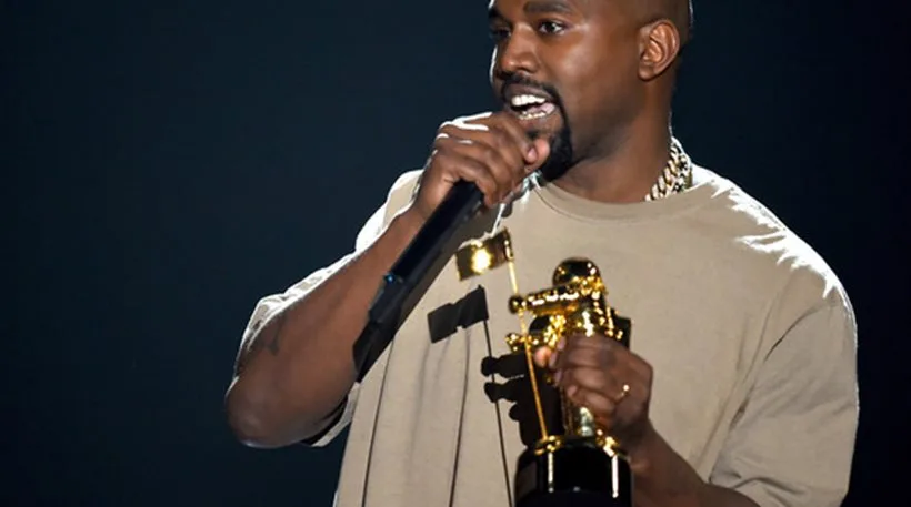 Ο Kanye West στη σκηνή των βραβείων MTV κρατώντας ένα βραβείο και μιλώντας στο μικρόφωνο.