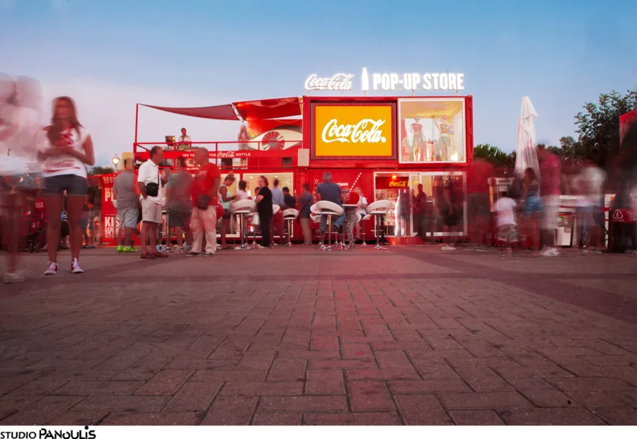 Το Coca-Cola Pop-Up Store με κόσμο να περιμένει απ' έξω το σούρουπο.