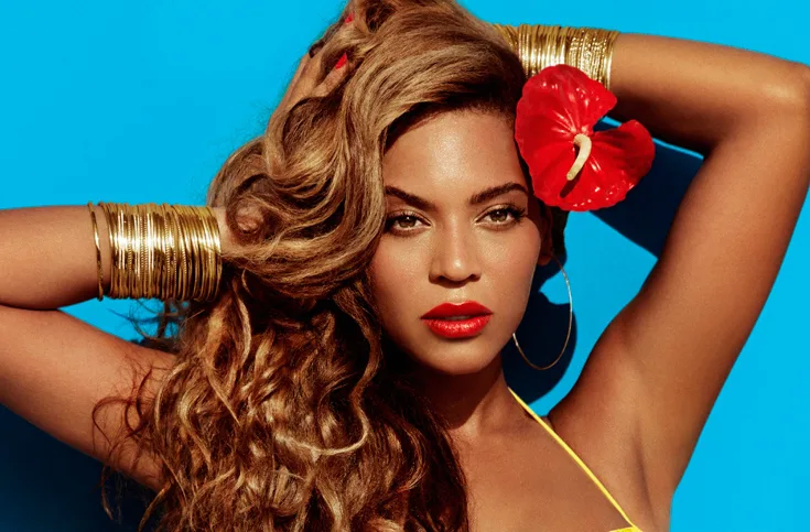 Η Beyoncé με χρυσά βραχιόλια και κόκκινο λουλούδι στα μαλλιά