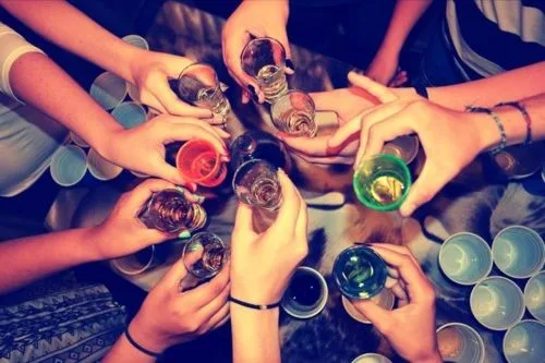 Παρέα φοιτητών που τσουγκρίζει σφηνάκια σε πάρτι.