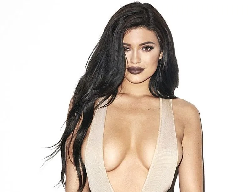 Η Kylie Jenner ποζάρει με μπεζ αποκαλυπτικό ένδυμα σε λευκό φόντο.