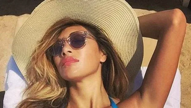 Η Nicole Scherzinger με ψάθινο καπέλο και γυαλιά ηλίου στην παραλία.
