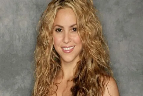 Η Shakira με μακριά ξανθά σπαστά μαλλιά σε γκρίζο φόντο