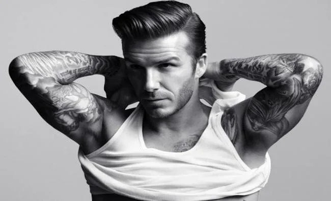 Ο David Beckham ποζάρει με τα χέρια πίσω από το κεφάλι, αναδεικνύοντας τα τατουάζ του.