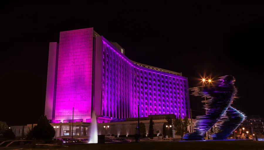 Το Hilton Αθηνών φωταγωγημένο με ροζ χρώμα τη νύχτα.