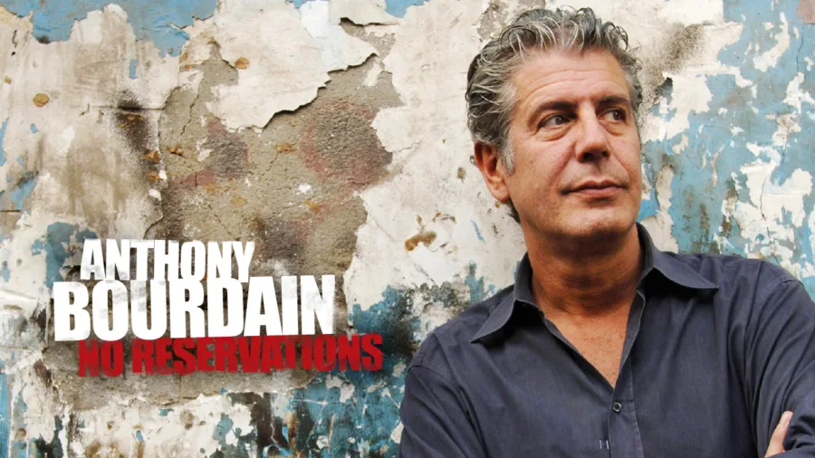 Ο Anthony Bourdain μπροστά από έναν φθαρμένο τοίχο.