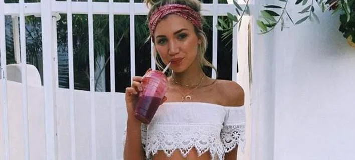 Η Γκάμπριέλ Επστέιν πίνει ένα smoothie φορώντας λευκό δαντελωτό τοπ και κορδέλα στα μαλλιά.