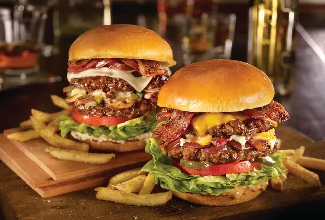Δύο μεγάλα burgers με μπέικον και τηγανητές πατάτες.