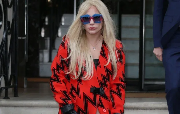Η Lady Gaga με κόκκινο παλτό και μπλε γυαλιά ηλίου