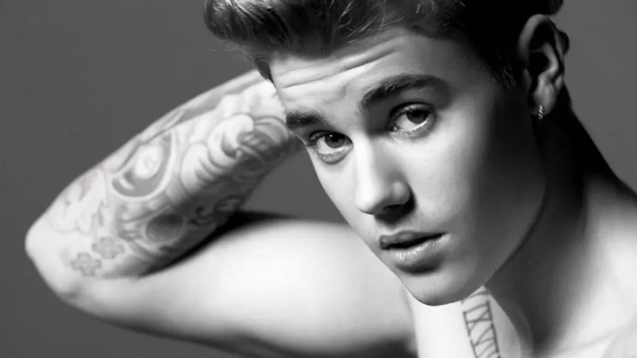 Ασπρόμαυρο κοντινό πορτρέτο του Justin Bieber με τατουάζ στο χέρι.