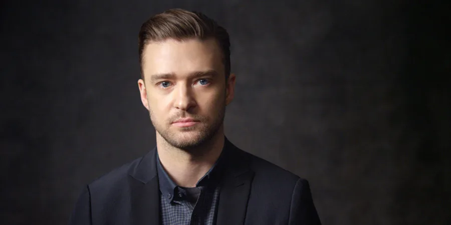 Ο Justin Timberlake με σκούρο κοστούμι και πουκάμισο σε γκρι φόντο.