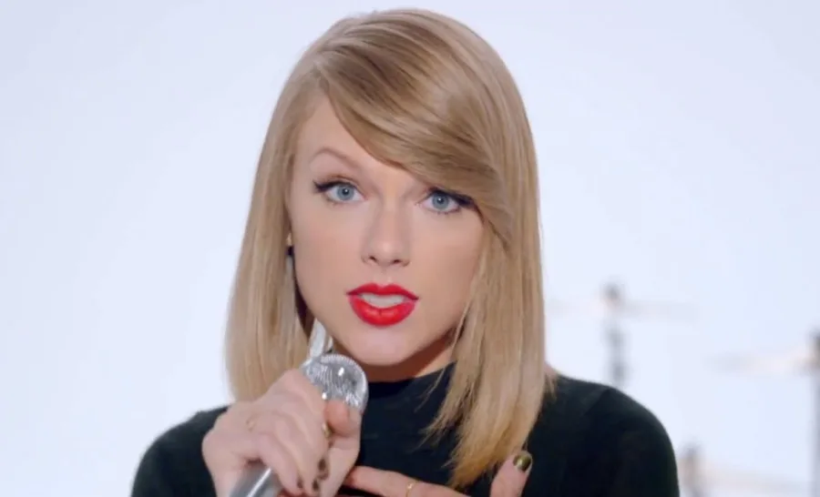 Η Taylor Swift τραγουδάει σε μικρόφωνο με κόκκινο κραγιόν.