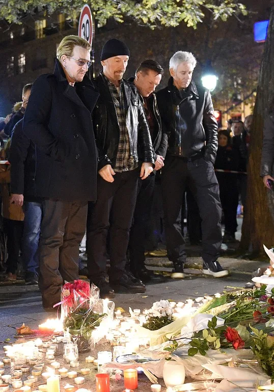 Irish band U2 (From L) lead singer Bono, guitarist The Edge, drummer Larry Mullen Jr and bass player Adam Clayton pay homage to attacks' victims near the Bataclan concert hall on November 14, 2015 in Paris, a day after a series of coordinated attacks in and around Paris. Islamic State jihadists claimed a series of coordinated attacks by gunmen and suicide bombers in Paris that killed at least 129 people in scenes of carnage at a concert hall, restaurants and the national stadium. U2 has canceled two sold-out concerts in Paris, including one to be broadcast live on November 14, and Foo Fighters cut short their tour after attacks that killed at least129 people. AFP PHOTO / FRANCK FIFE