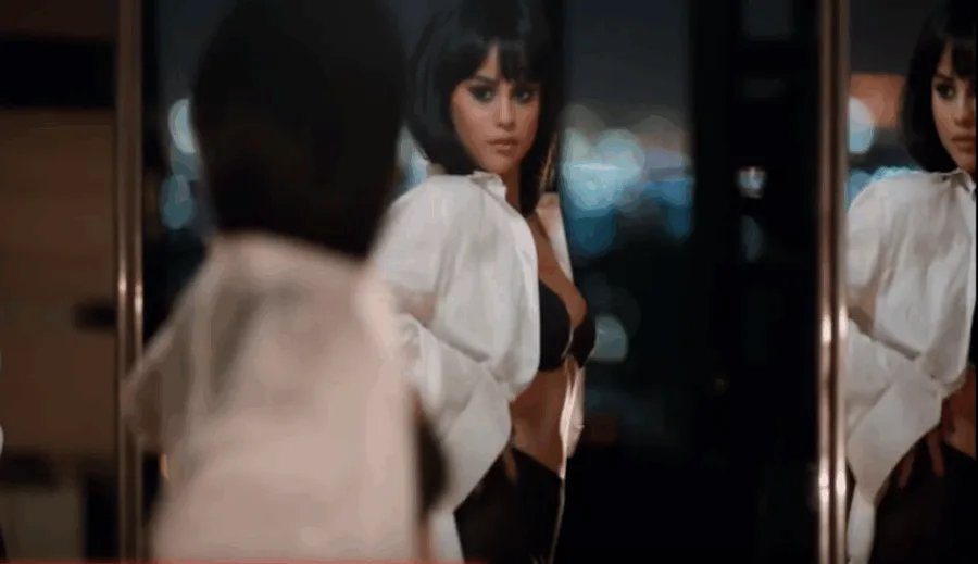 Η Selena Gomez με λευκό πουκάμισο και μαύρα εσώρουχα μπροστά σε καθρέφτη.