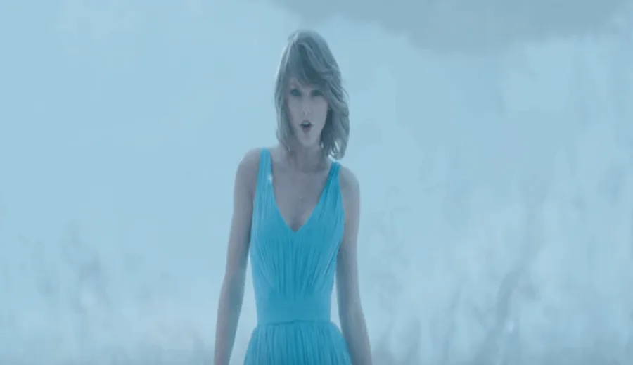 Η Taylor Swift με γαλάζιο φόρεμα σε ομιχλώδες τοπίο από το βίντεο κλιπ Out of the Woods.