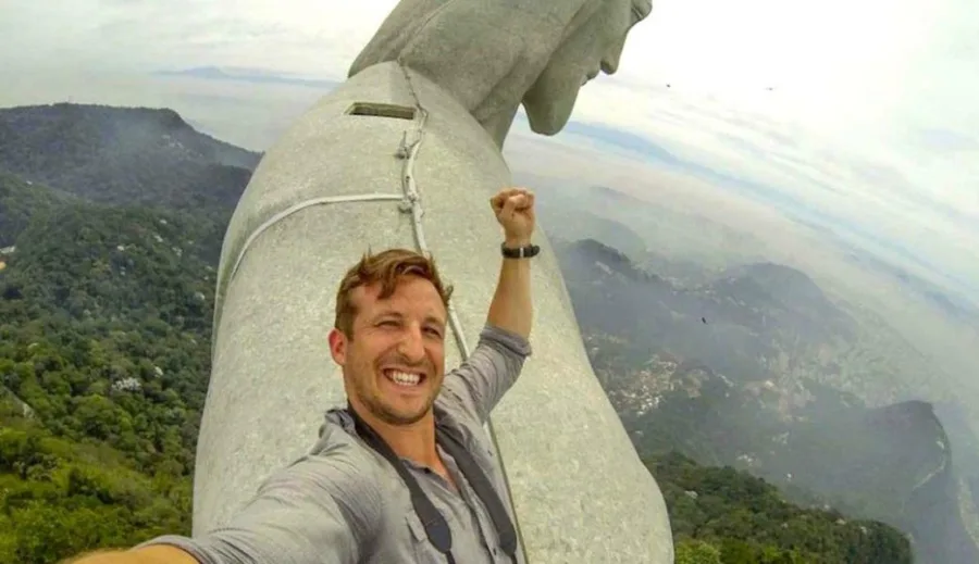 Άνδρας βγάζει selfie πάνω στον ώμο του αγάλματος του Χριστού Λυτρωτή στο Ρίο ντε Τζανέιρο.