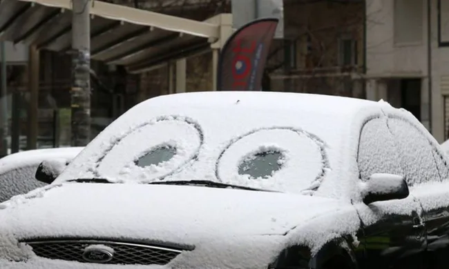 Αυτοκίνητο Ford καλυμμένο με χιόνι και σχέδια ματιών στο παρμπρίζ.