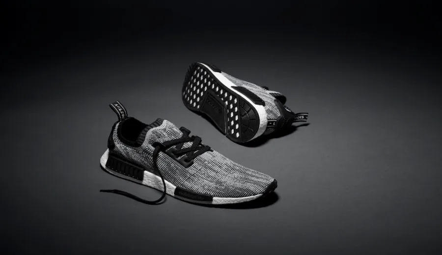 Τα αθλητικά παπούτσια adidas Originals NMD_R1 Primeknit σε γκρι και μαύρο χρώμα.