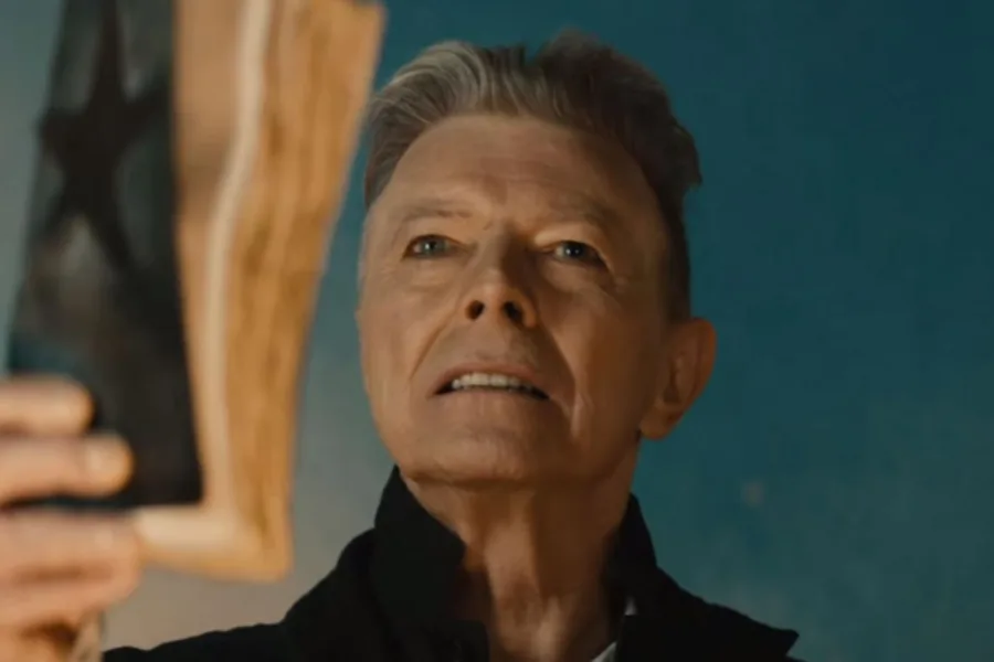 Ο David Bowie κρατά ένα βιβλίο με ένα μαύρο αστέρι στο εξώφυλλο.