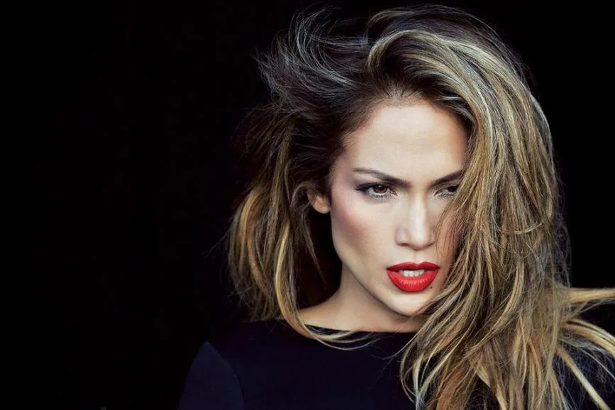 Κοντινό πορτρέτο της Jennifer Lopez με έντονο κόκκινο κραγιόν και ξανθές ανταύγειες.