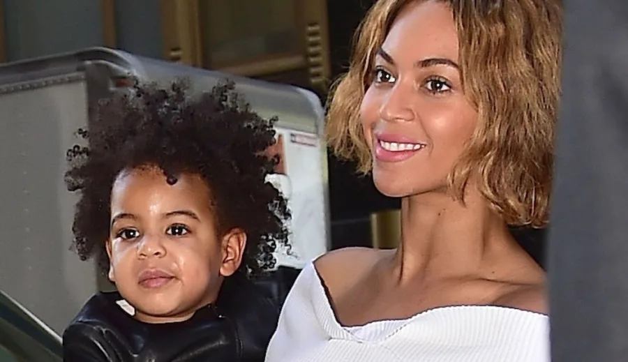 Η Beyoncé χαμογελάει κρατώντας στην αγκαλιά της την κόρη της Blue Ivy.