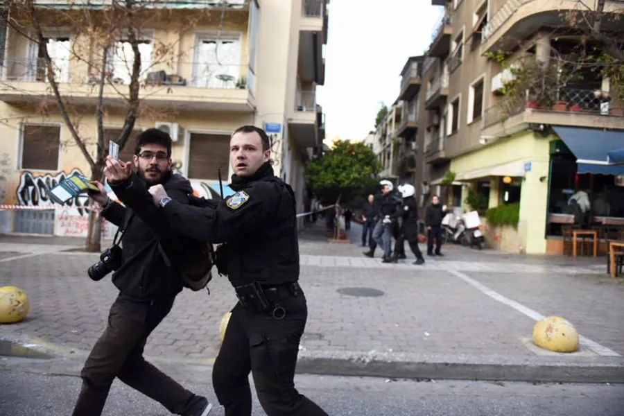 Αστυνομικός απωθεί φωτορεπόρτερ σε δρόμο της Αθήνας.
