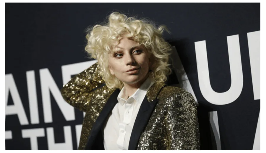 Η Lady Gaga με σγουρή ξανθιά περούκα και χρυσό σακάκι στο σόου του Saint Laurent.