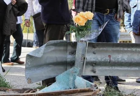 Λουλούδια και σπασμένα γυαλιά σε μπάρα οδικής ασφάλειας.