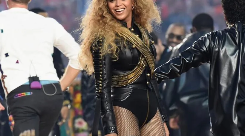 Η Beyoncé στη σκηνή με μαύρο κορμάκι και χρυσές λεπτομέρειες.