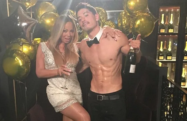 Η Mariah Carey σε πάρτι γενεθλίων με έναν άνδρα και χρυσά μπαλόνια.