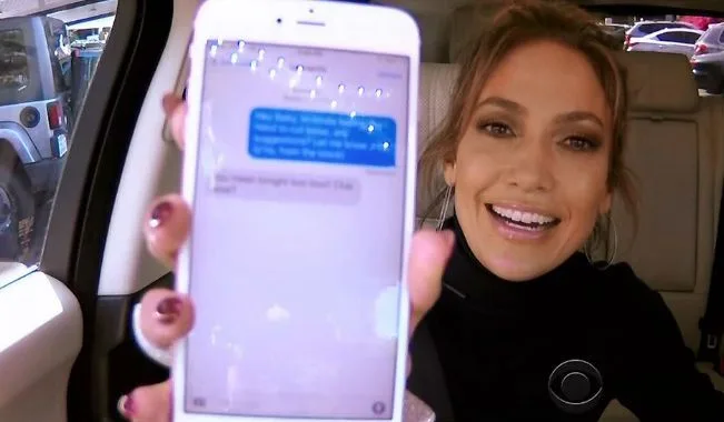 Η Jennifer Lopez δείχνει την οθόνη ενός κινητού τηλεφώνου μέσα σε αυτοκίνητο.
