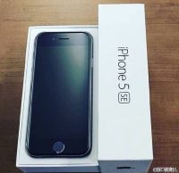 Ένα iPhone 5se δίπλα στη συσκευασία του πάνω σε ξύλινη επιφάνεια.