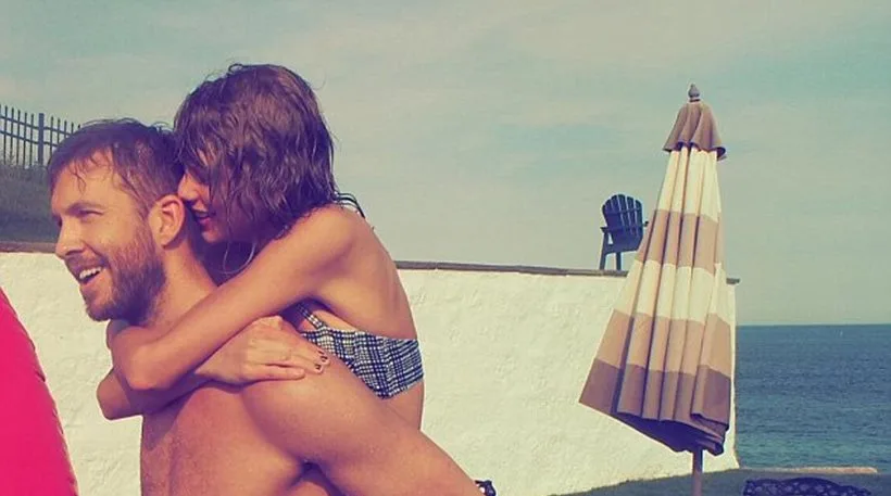 Η Taylor Swift κάνει piggyback στον Calvin Harris σε εξωτερικό χώρο κοντά στη θάλασσα.