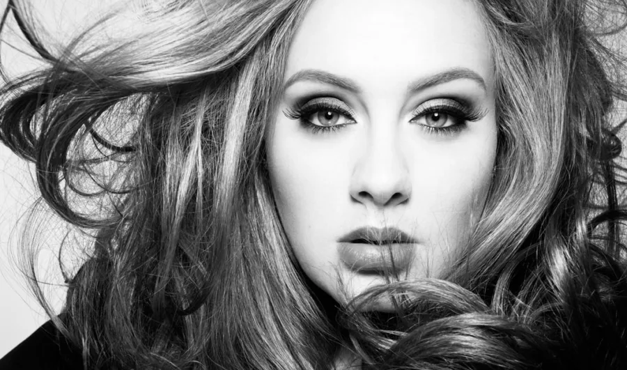 Ασπρόμαυρο κοντινό πορτρέτο της Adele με έντονο μακιγιάζ και ατημέλητα μαλλιά.